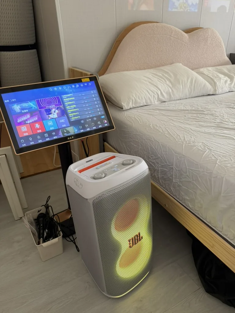 雲朵房床邊的觸控 KTV 點歌機、白色 JBL 喇叭與麥克風收納盒