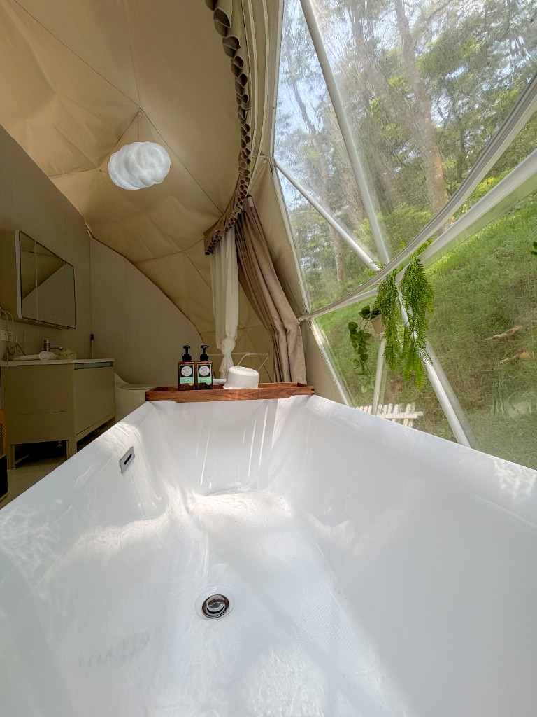 雲朵房帳內從浴缸望向透明球體窗外森林景觀，洗沐備品與雲朵燈搭配，桃園楊梅森林豪華露營 GLAMPING｜揪好森
