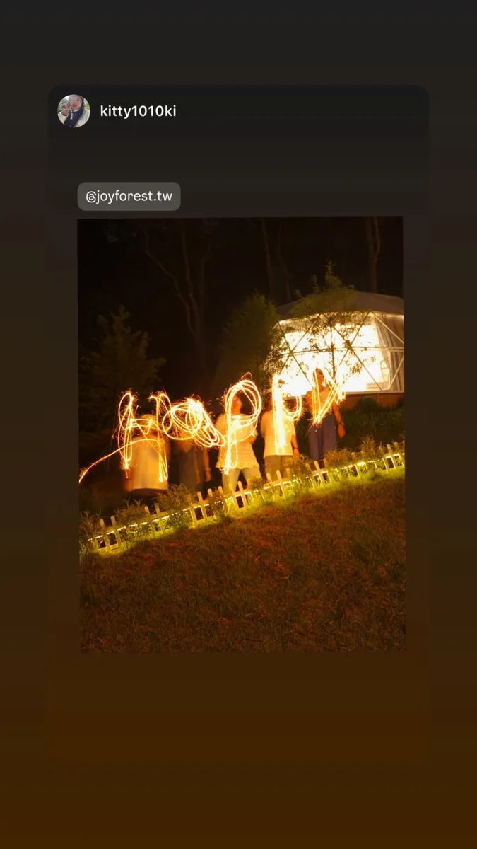 好友站在夜間發亮的圓頂帳篷前，以長曝光留下橘色光線圖案