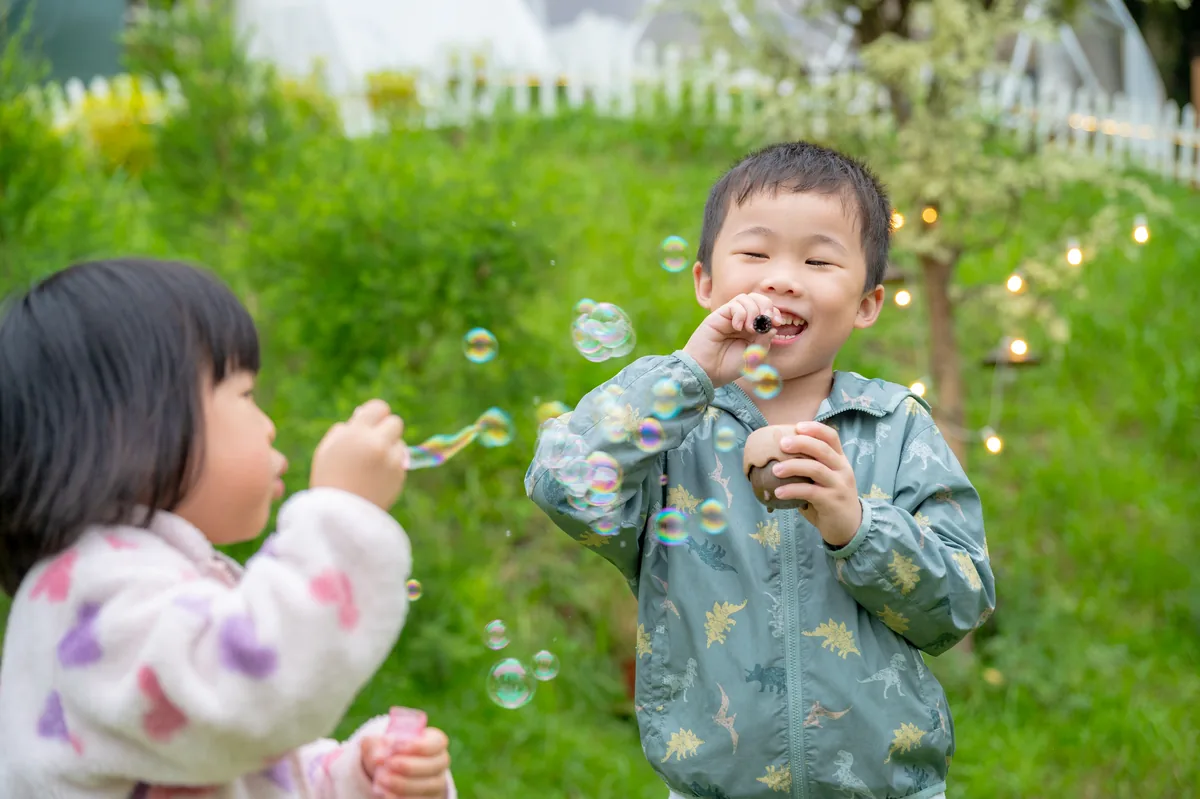 男孩與女孩在營區草地上分享泡泡玩具
