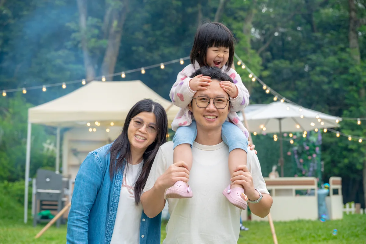 女兒坐在爸爸肩膀上與媽媽一起散步