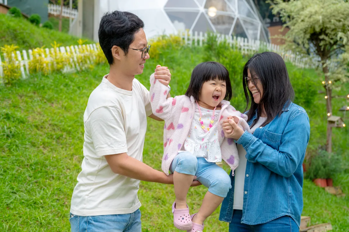 一家三口在森林草地上開心相視而笑