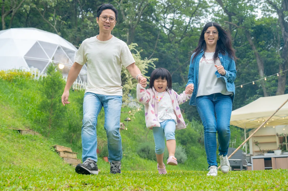 爸爸媽媽牽著女兒走過揪好森草地