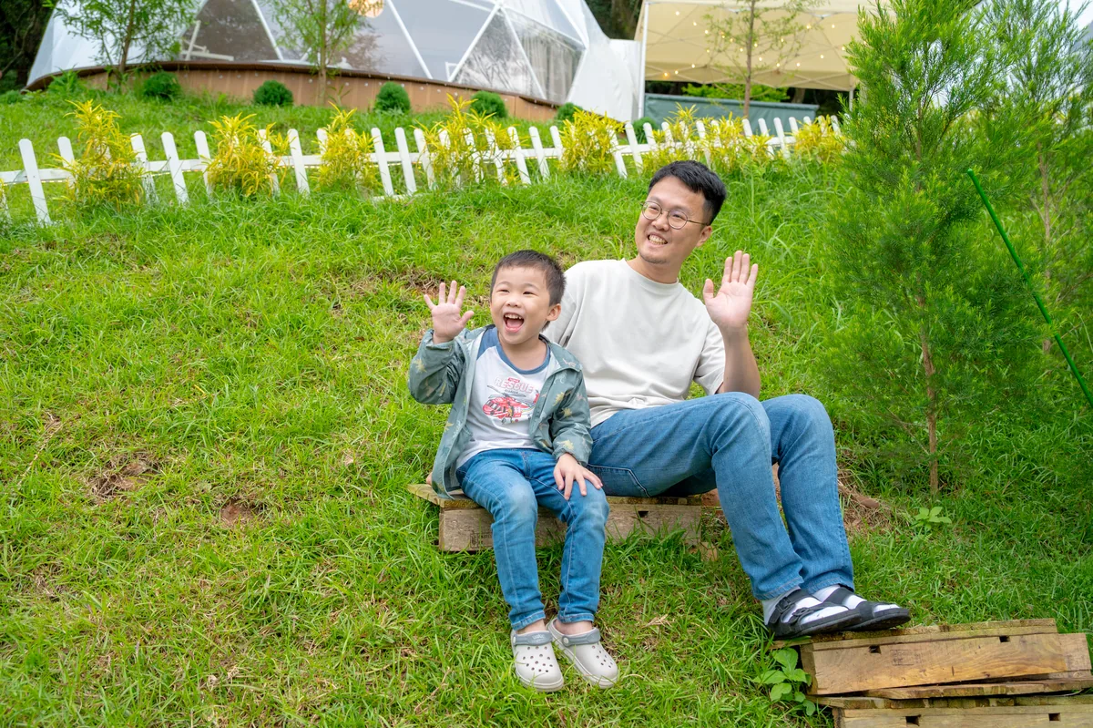 爸爸與兒子坐在森林草地上輕鬆互動