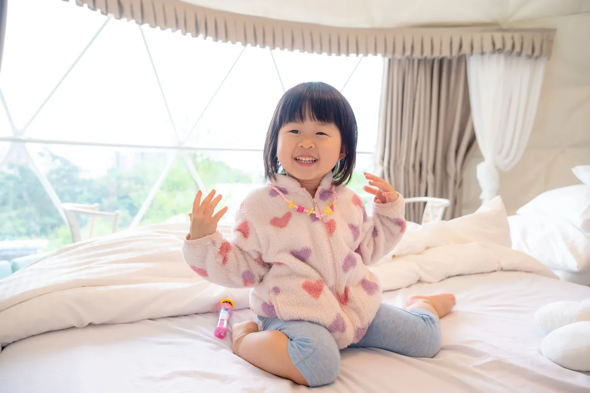小女孩坐在圓頂帳篷床上開心玩耍