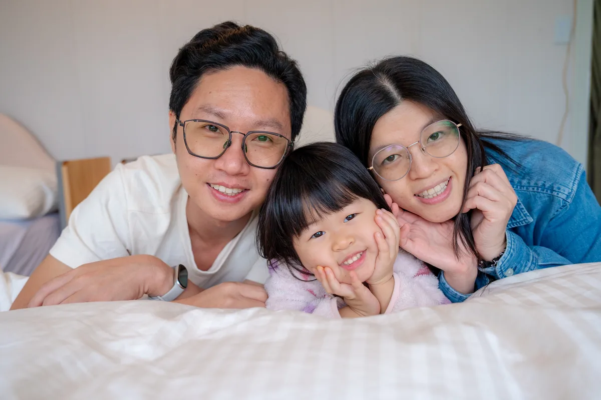 爸爸媽媽與女兒一起躺在帳篷床上合照