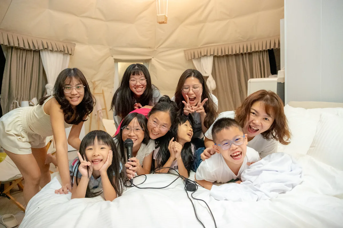 員工與孩子們在圓頂帳篷床邊笑著拍攝活潑團體照