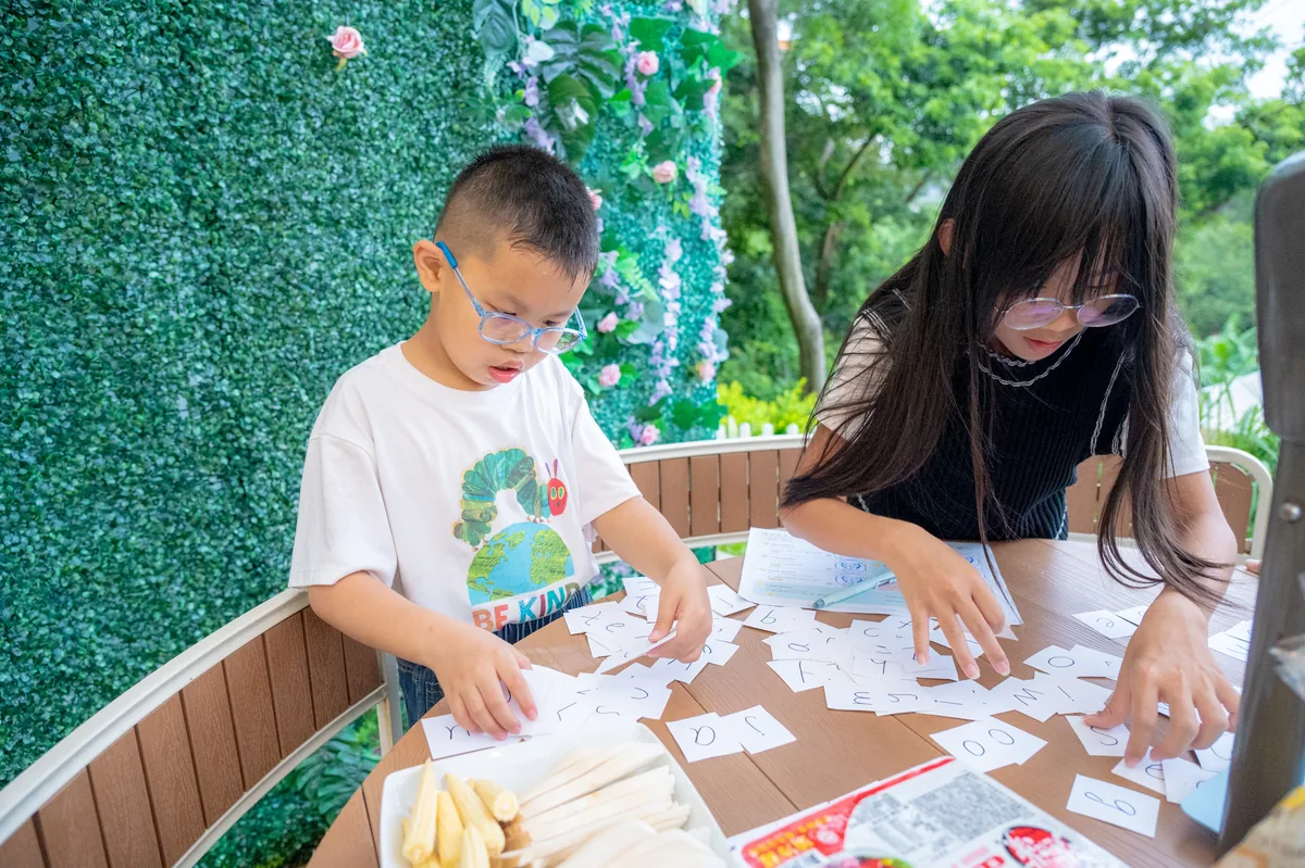 孩子在戶外圓桌上用字卡進行英文拼字遊戲