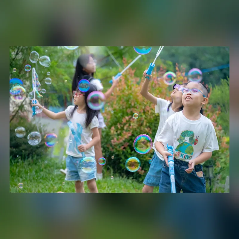 昕閱森林英語員工旅遊中孩子們在草地一起玩泡泡的正方形縮圖