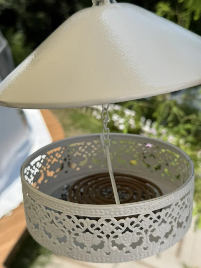 Open metal mosquito coil holder with a coil secured inside